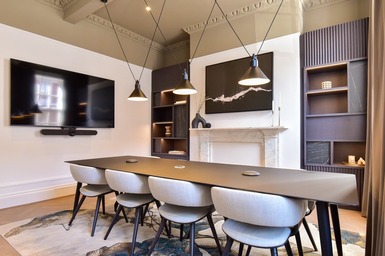 Boardroom with fireplace, dark joinery and wall-mounted screen