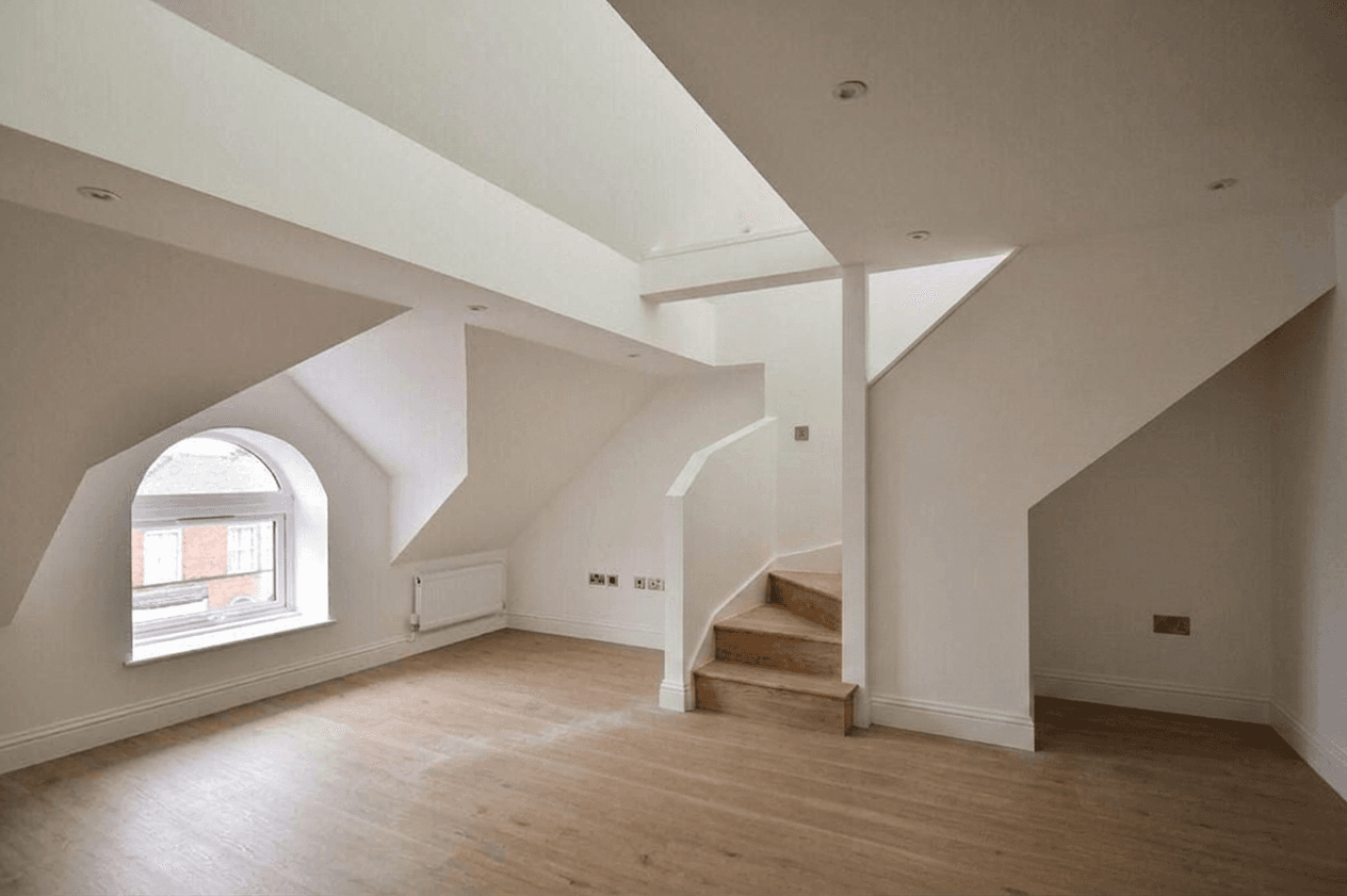 Top-floor living space with an oak stair and arched window